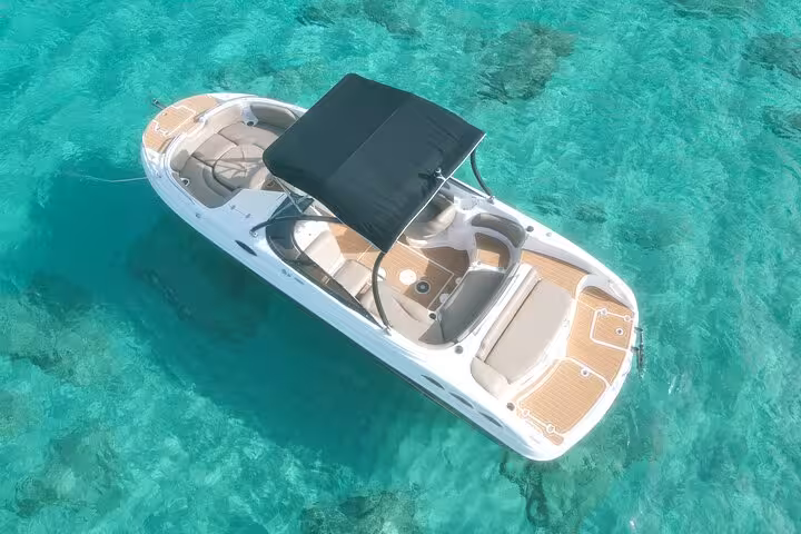Aerial view of a luxury boat floating on crystal-clear waters near Cala Bassa and Cala Comte, perfect for a premium sea tour.