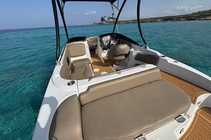 Luxurious boat with spacious seating cruising through turquoise waters on Cala Bassa and Cala Comte tour.