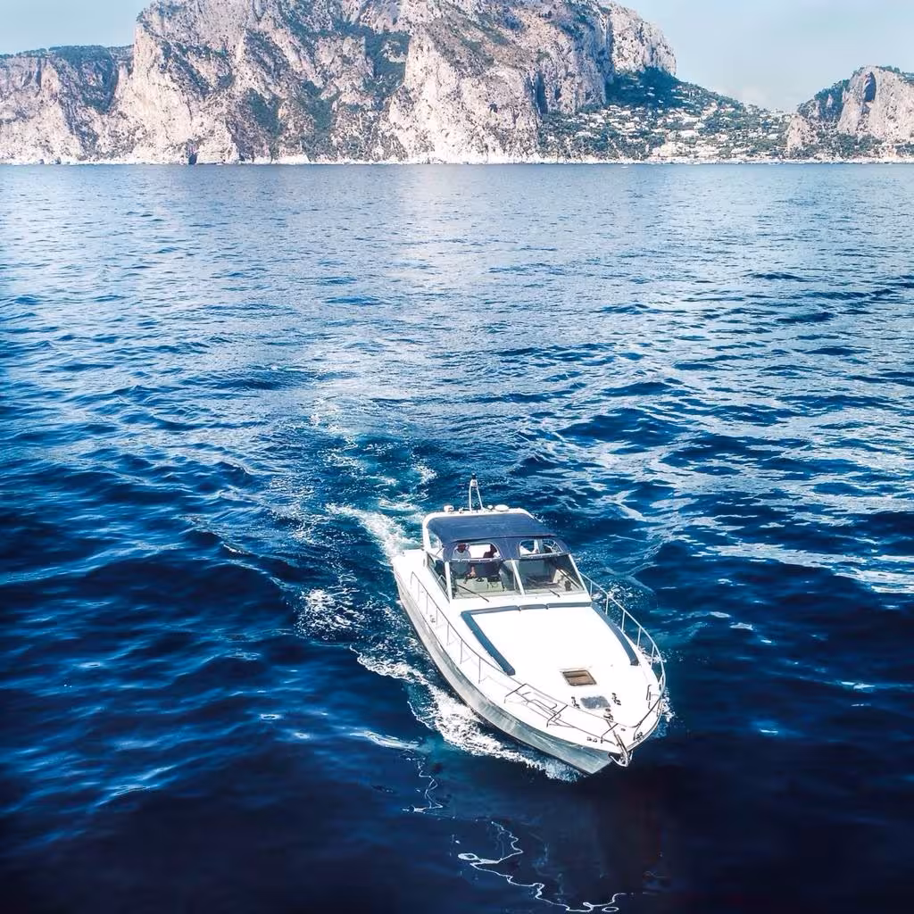 Luxury boat cruising towards Capri's stunning cliffs on an exclusive private tour from Sorrento.