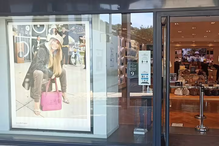 Entrance to a luxury boutique at The Mall outlet near Florence, showcasing designer handbags and upscale shopping displays