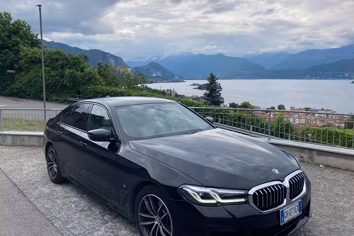 Luxury car parked by a scenic lake view on a private transfer from Rome to Fiumicino Airport.