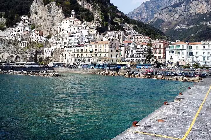Colorful cliffside village and seafront promenade viewed from the harbor on a luxury Amalfi Coast catamaran cruise