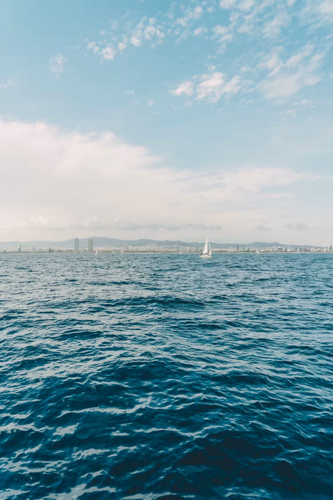 Mediterranean sea view from a private luxury catamaran cruise in Barcelona, with skyline on the horizon