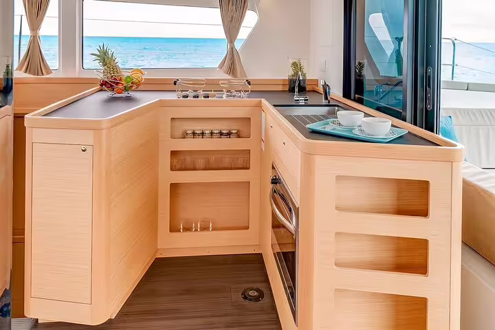 Luxurious catamaran interior with modern kitchen and ocean view, perfect for a sunset tour around Madeira Island.