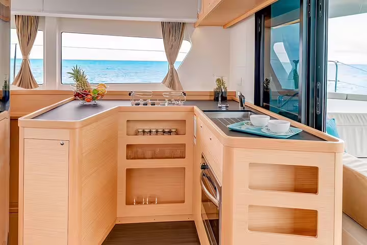 Luxurious interior of a catamaran with ocean view, featuring a modern kitchen setup for a half-day tour on Madeira Island.