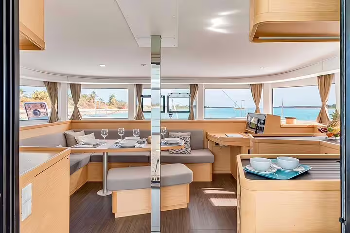 Spacious interior of a luxury catamaran with elegant dining setup, offering panoramic ocean views on a Madeira Island sunset tour.