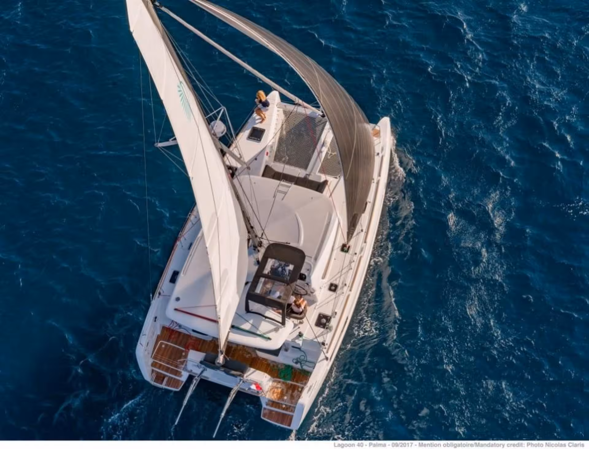Aerial view of a luxurious catamaran sailing through the clear blue waters of the La Maddalena archipelago.