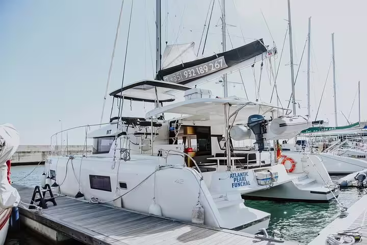 Luxurious catamaran docked in Madeira Island marina, ready for a half-day tour exploring scenic coastlines and crystal-clear waters.