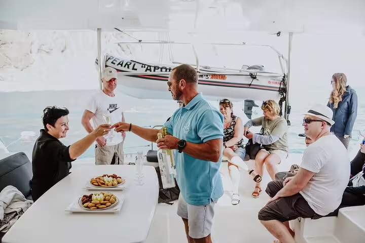 Guests enjoying drinks and snacks on a luxury catamaran during a scenic half-day tour on Madeira Island's stunning waters.