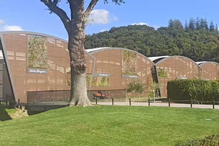 Modern curved outlet buildings with lush lawns and designer stores at Prada Space and The Mall Tuscany on chauffeured tour