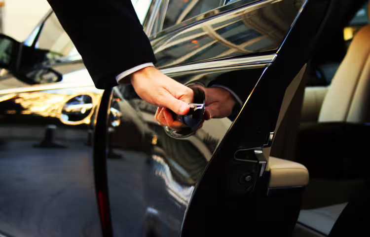 Chauffeur opening sleek black luxury car door for private transfer from central Rome hotel to Fiumicino Airport