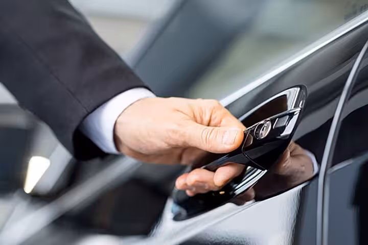 Close-up of a chauffeur opening a luxury car door for a private transfer from Sorrento to Positano.