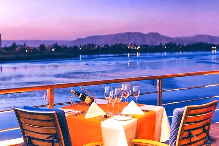 Romantic sunset dinner setup on private luxury Dahabiya Nile cruise deck during 5 days 4 nights Abu Simbel tour