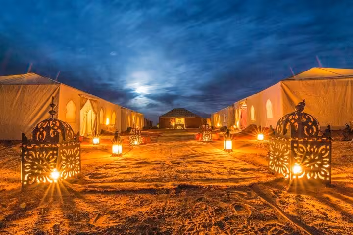 Luxurious desert camp illuminated at night under a starry sky on a 2-day tour from Fes to Marrakech.