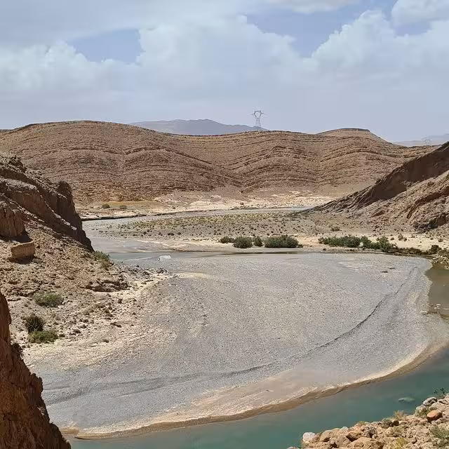 Scenic view of winding river through rocky desert landscape on luxury tour from Errachidia to Fes via Merzouga Erg Chebbi.