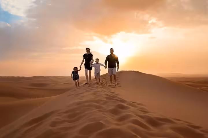 Family enjoying sunset on sand dunes during 2-day luxury desert tour from Fes to Marrakech.