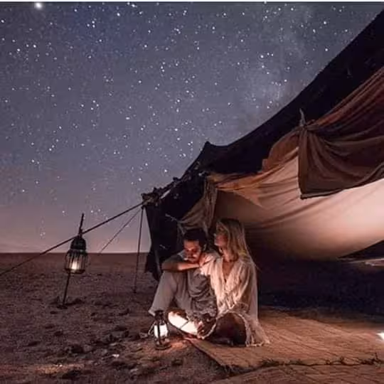 Couple enjoys a starlit night in a cozy tent on the luxury desert tour from Errachidia to Fes via Merzouga.