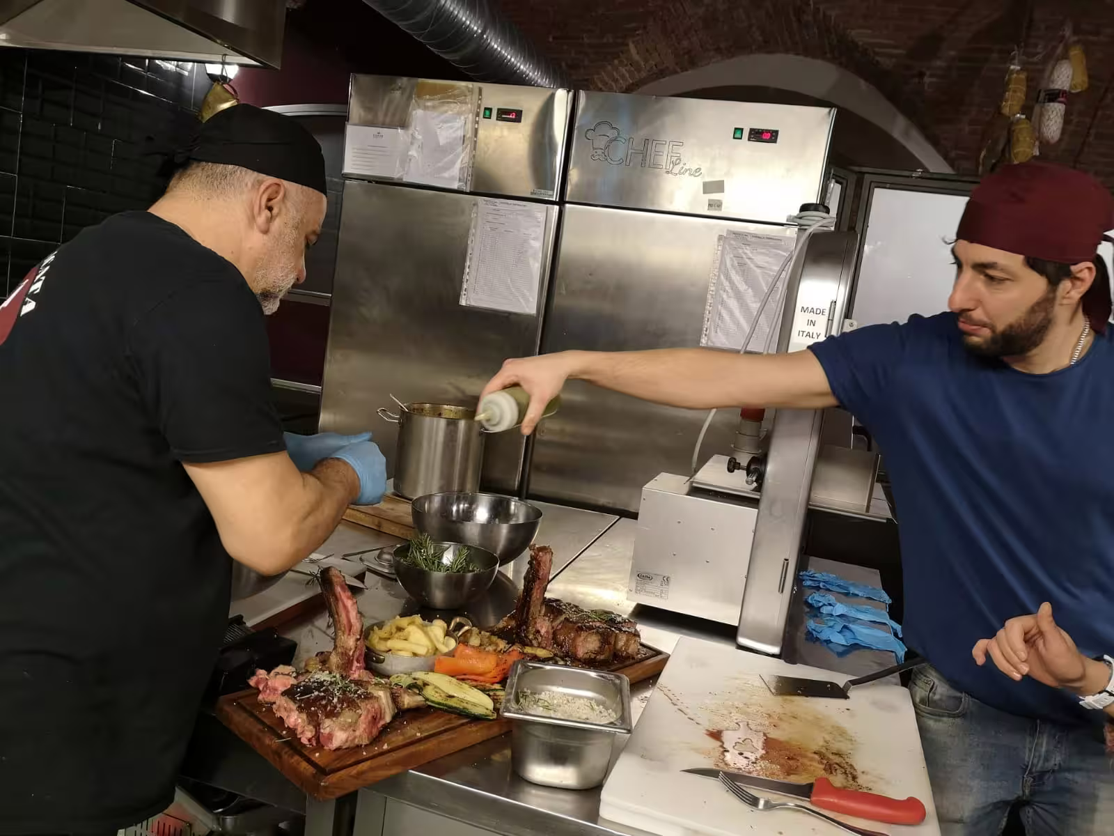 Chefs preparing a gourmet meat dish in a luxury cooking class, emphasizing hands-on culinary expertise.