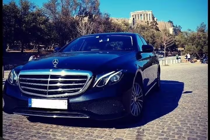 Luxury Mercedes sedan for private transfer from Delphi to Athens, Greece, with Acropolis in the background