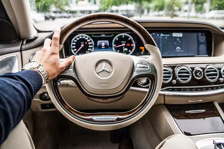 Luxury Mercedes interior with private chauffeur driving through Muscat, showcasing premium airport and hotel transfer service