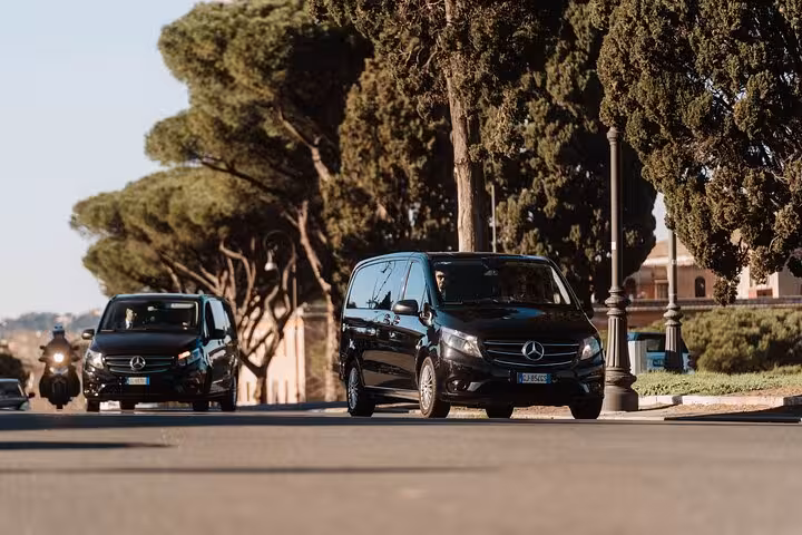 Luxury Mercedes vans driving through scenic Rome streets, part of the private transfer service to Pompeii.