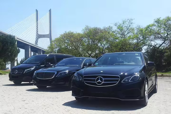 Luxury Mercedes vehicles for Sintra and Cascais customizable full-day tour with private driver, parked near Lisbon bridge.