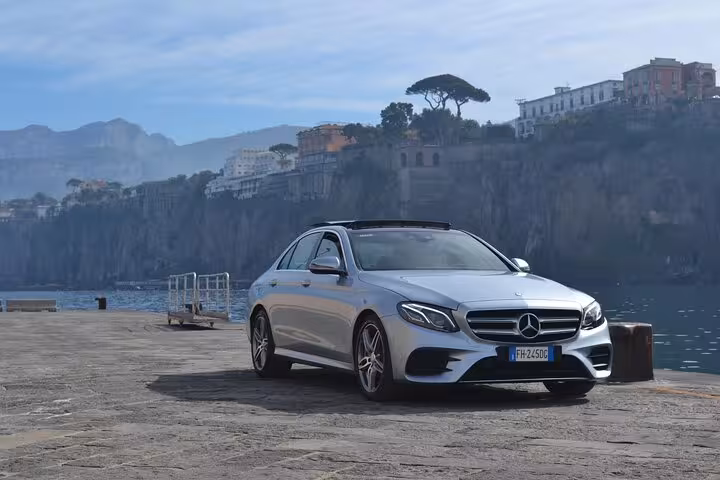 Luxury Mercedes car parked by scenic Sorrento cliffs for private transfer to Positano.
