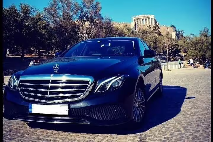 Luxury Mercedes sedan for private transfer from Thessaloniki to Athens, parked near Athens landmarks