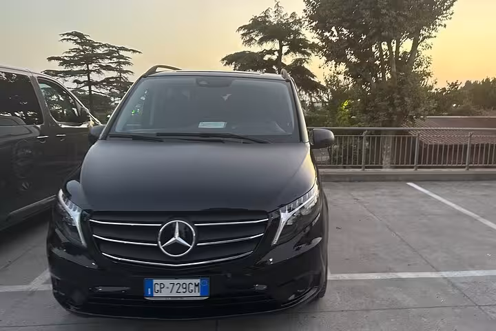 Luxury Mercedes van for private transfer from Amalfi Coast to Rome, parked against a scenic sunset backdrop.