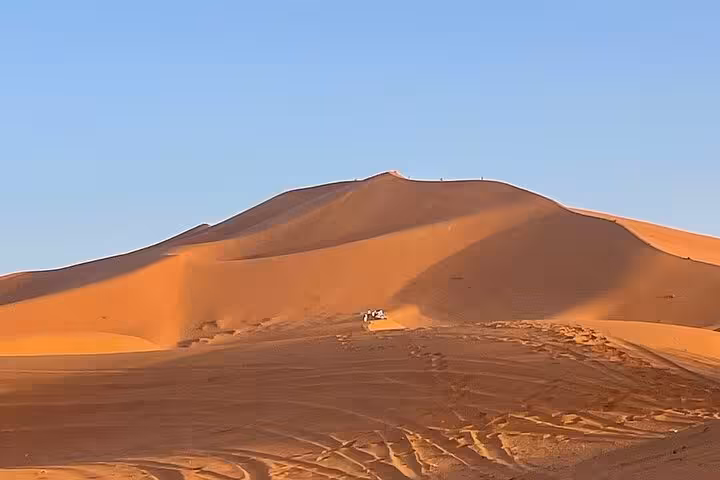 Expansive view of golden sand dunes at sunrise in Morocco's desert, showcasing luxury tour landscapes from Fes.