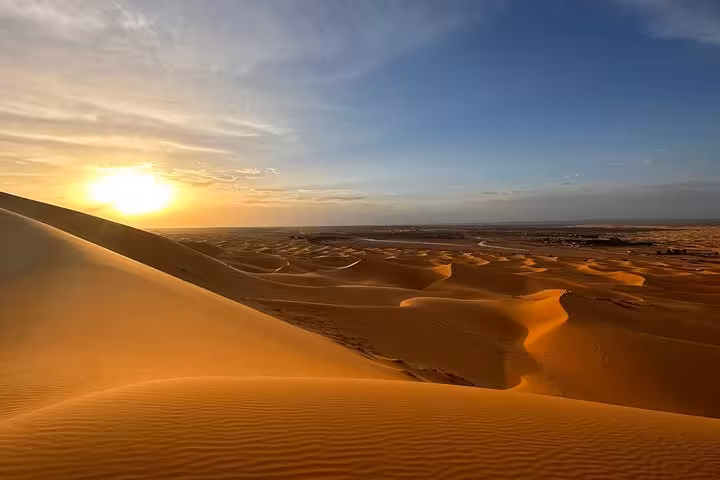 Breathtaking sunset over the golden sand dunes of the Moroccan desert, a highlight of the luxury tour from Fes.