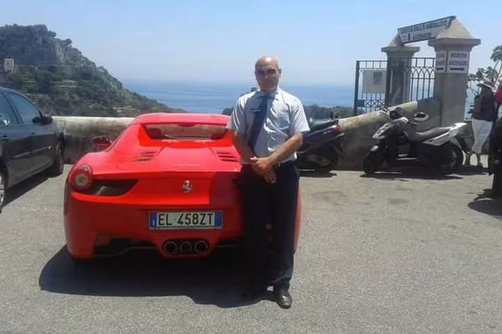 Professional chauffeur beside red sports car overlooking Tyrrhenian Sea on luxury Rome to Naples private transfer