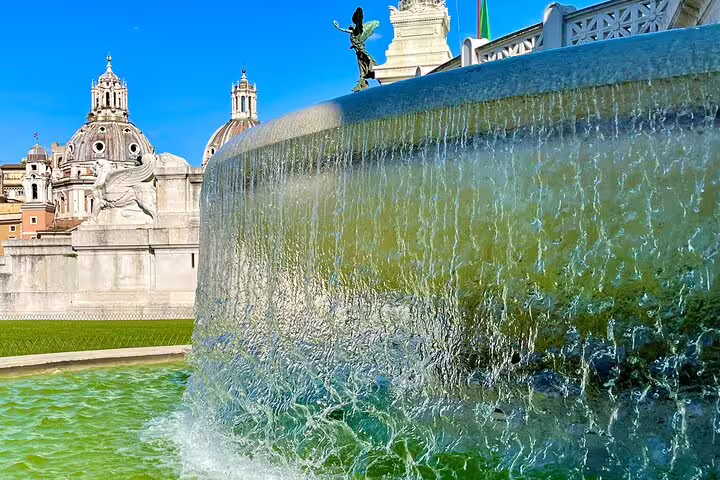 Luxury Rome city tour stopping at a grand cascading fountain near Piazza Venezia with domed churches in the background
