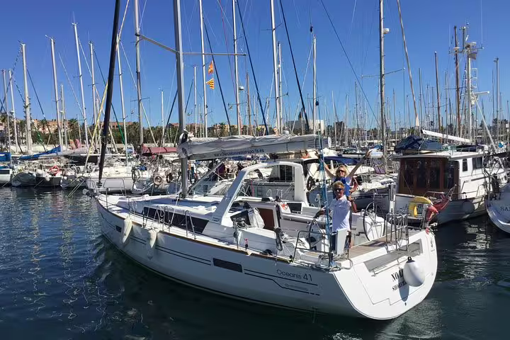 Luxurious sailboat in a bustling marina, ready for a 2-hour sailing adventure with drinks, snacks, and swimming.