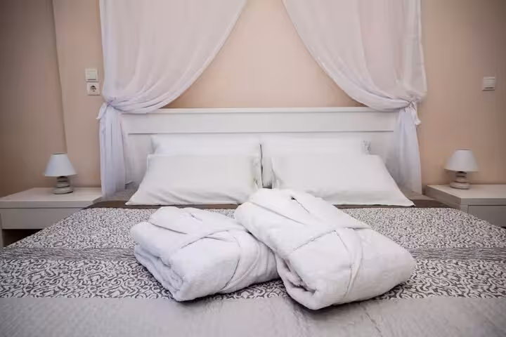 Luxury Santorini villa bedroom with king bed and plush bathrobes for day getaway stay with transfers