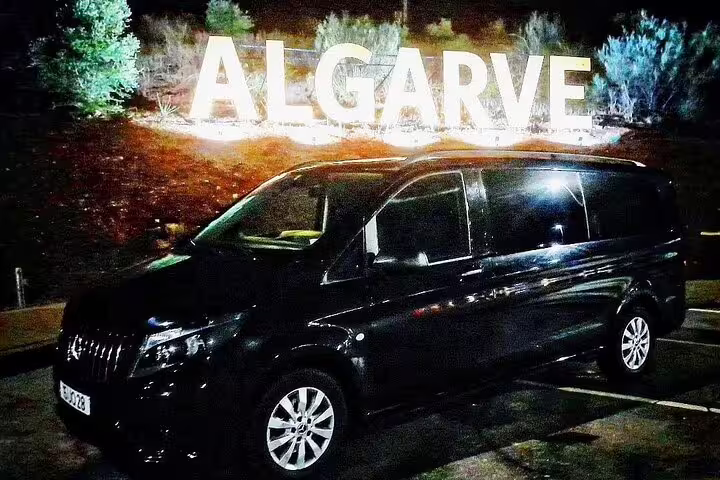 Luxury van parked at night near illuminated Algarve sign, perfect for private tours from Lisbon to Lagos and Sagres.