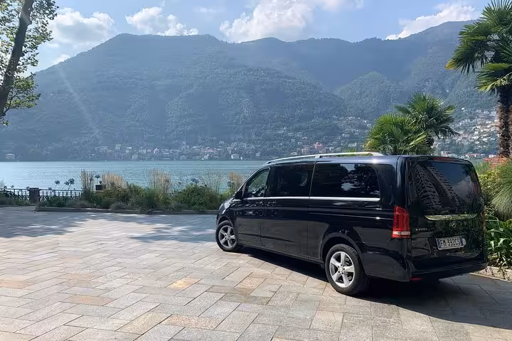 Luxury van parked by scenic lake view on Milan to Courchevel private transfer route.