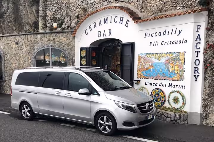 Luxury van parked outside a charming ceramic shop, ideal for private transfers from Naples to Sorrento.