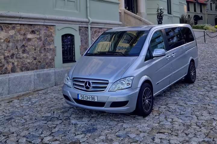 Luxurious silver van on cobblestone street, ideal for private transfer between Porto and Lisbon.