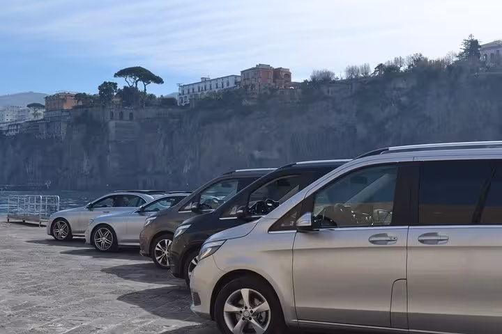 A row of luxury vehicles parked by the scenic cliffs of Sorrento, ideal for private transfers to Positano.