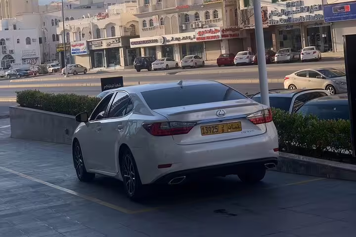 Luxury white Lexus parked on a bustling street in Muscat, ideal for private chauffeur-driven tours.
