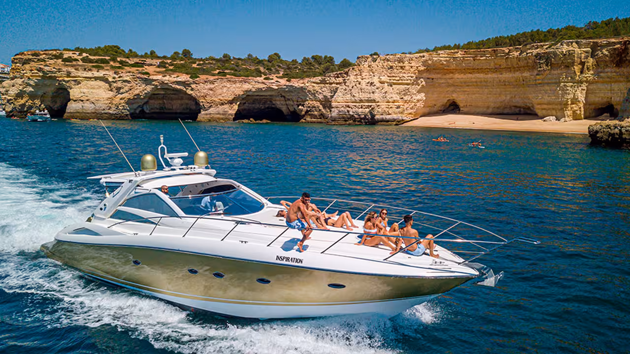 Luxury yacht with sunbathing guests cruising Algarve coastline caves on Morning Cruise Plus boat tour
