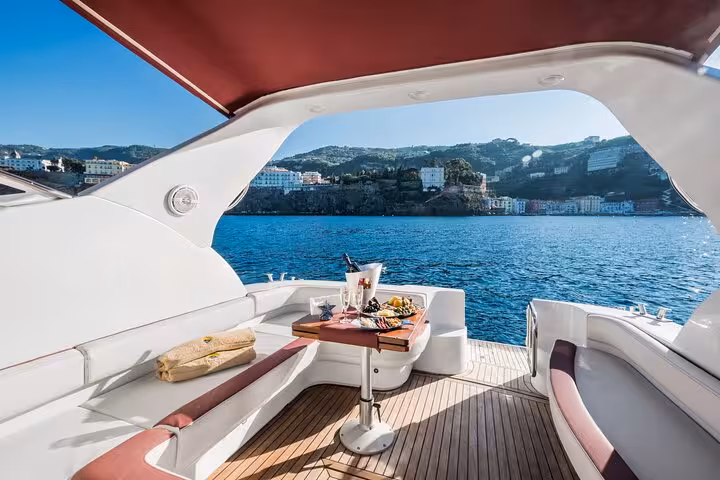 Panoramic view from luxury yacht's deck with dining setup, showcasing Capri's captivating coastline near Sorrento.