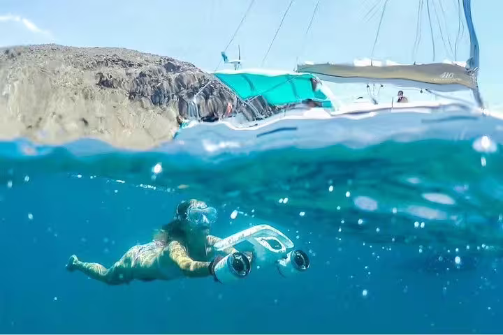 Snorkeler exploring underwater near a luxury yacht, showcasing vibrant marine life and clear waters.