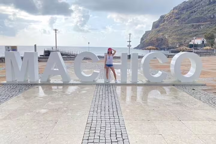 Tourist enjoying the Machico sign on Madeira's scenic coast during a full-day East of Madeira tour.