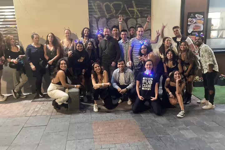 A lively group enjoying the Madrid nightlife on a Mad Party Crew pub crawl, featuring socializing, fun, and illuminated accessories.
