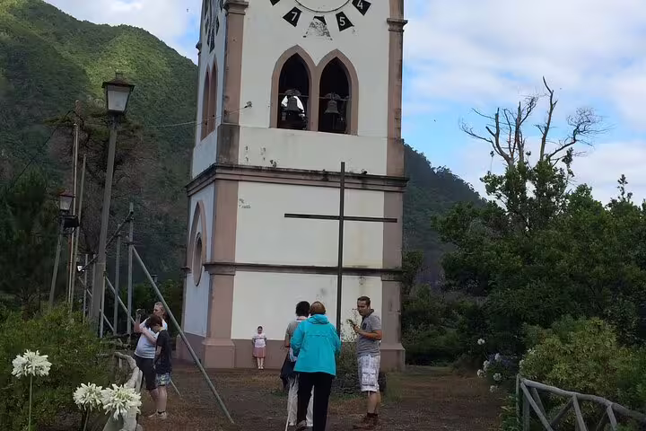 Tourists explore a historic clock tower surrounded by lush greenery during a 4x4 adventure tour in scenic Madeira.
