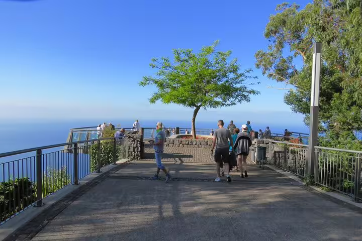 Tourists enjoy panoramic ocean views from a scenic skywalk in Madeira, surrounded by lush greenery, during a 4x4 adventure.