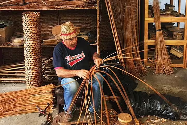 Artisan weaving traditional wicker basket in Madeira during full day east tour showcasing local crafts.