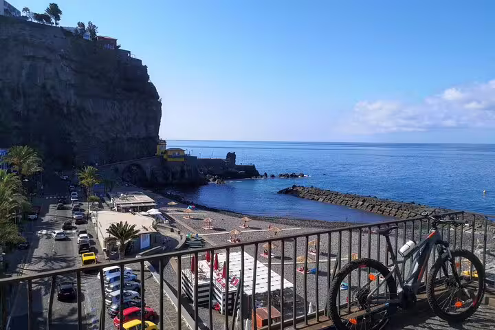 E-bike parked on a scenic viewpoint overlooking Madeira's stunning north coast, with cliffs, beach, and ocean views.